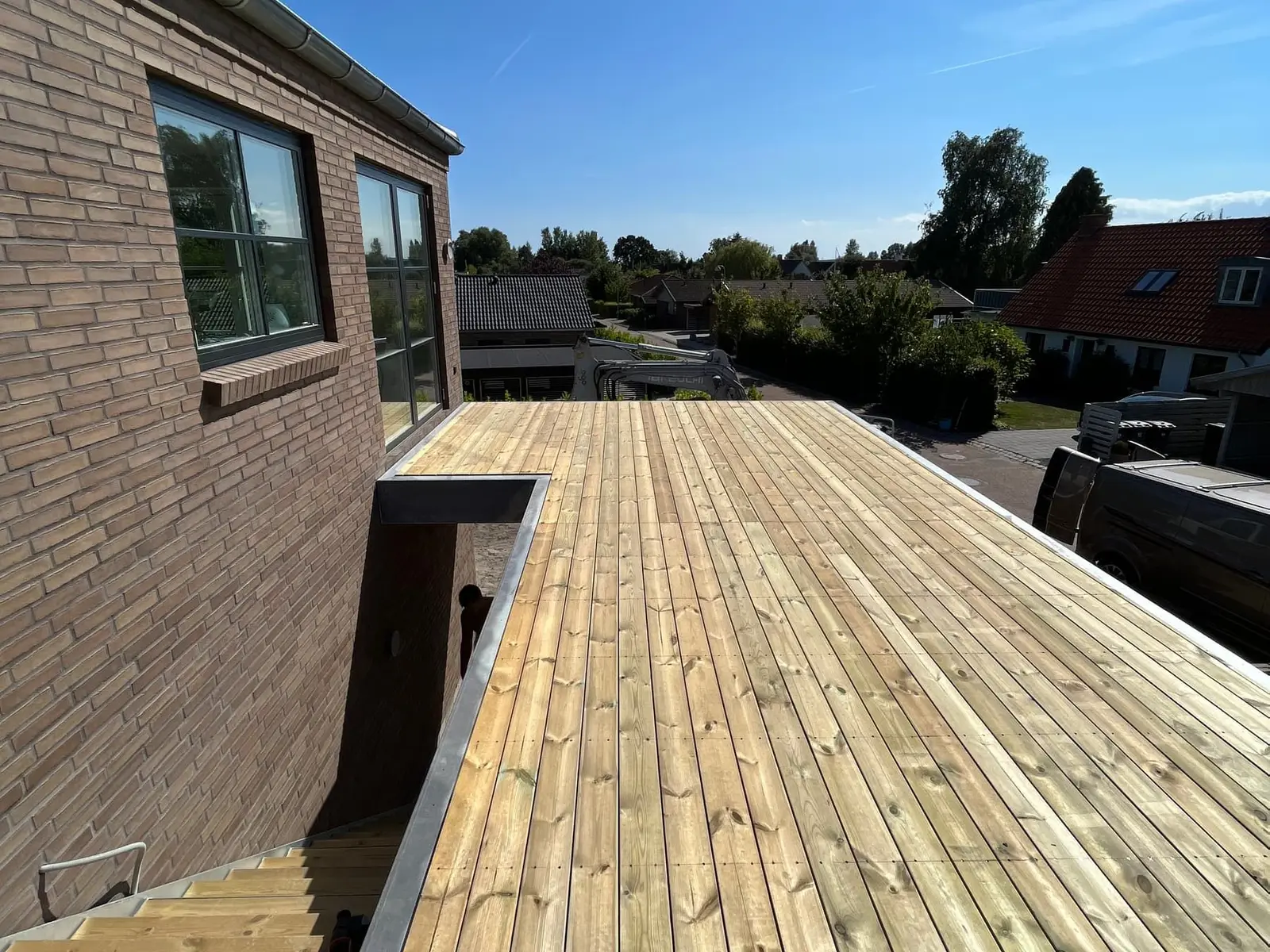 Ny træterrasse langs et murstenshus