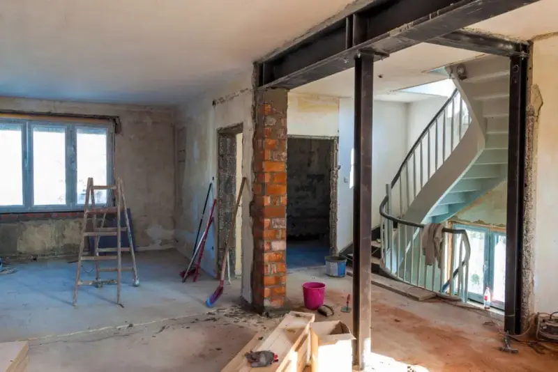Hus under renovering med blotlagte mursten og en stålbjælke